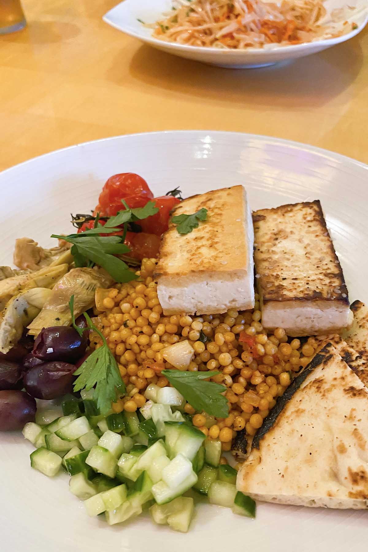 Israeli couscous with veggies and tofu in a white bowl