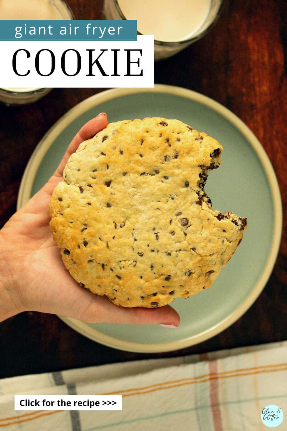 hand holding a giant, vegan air fryer cookie with a bite taken out. Text overlay.