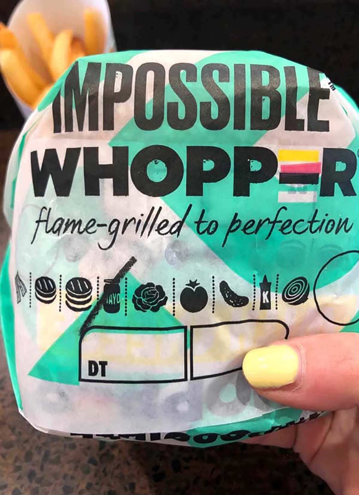 hand holding an Impossible Whopper in the wrapper