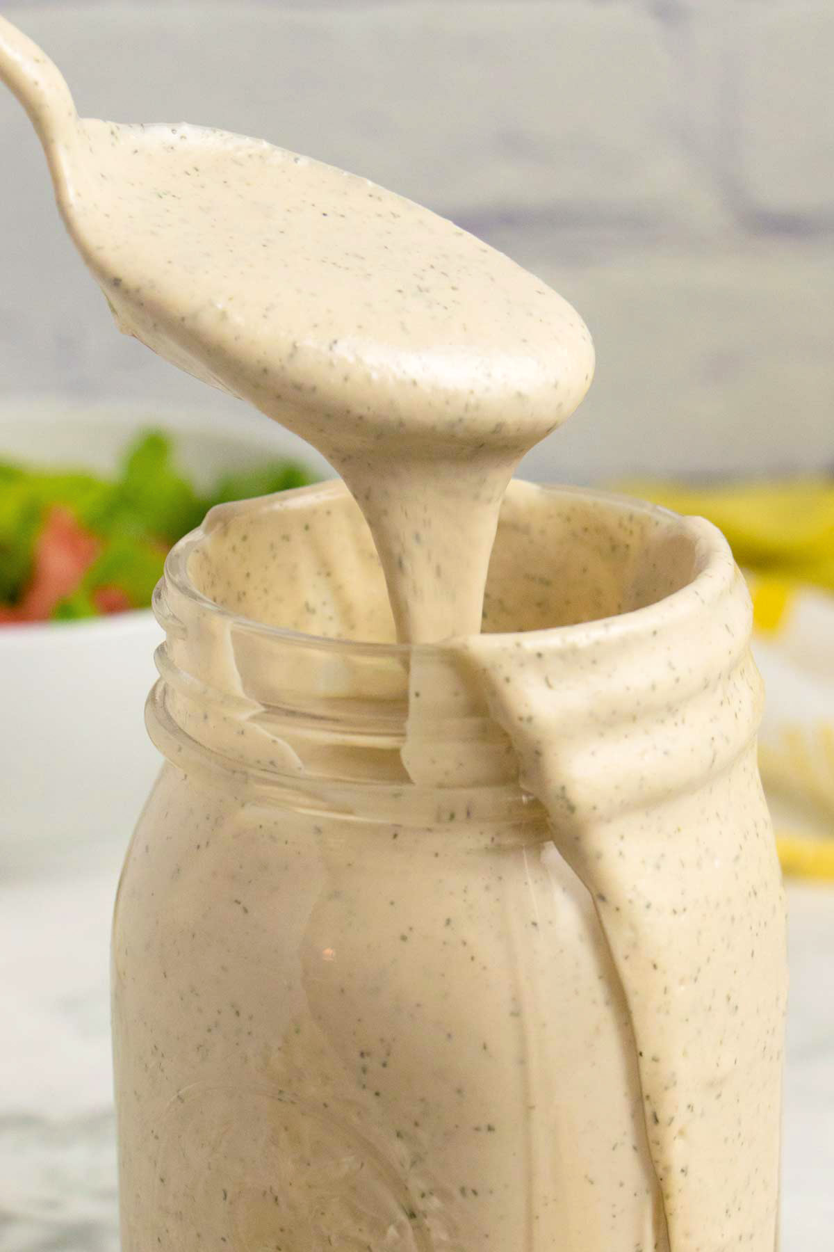 spooning tahini ranch dressing out of a mason jar
