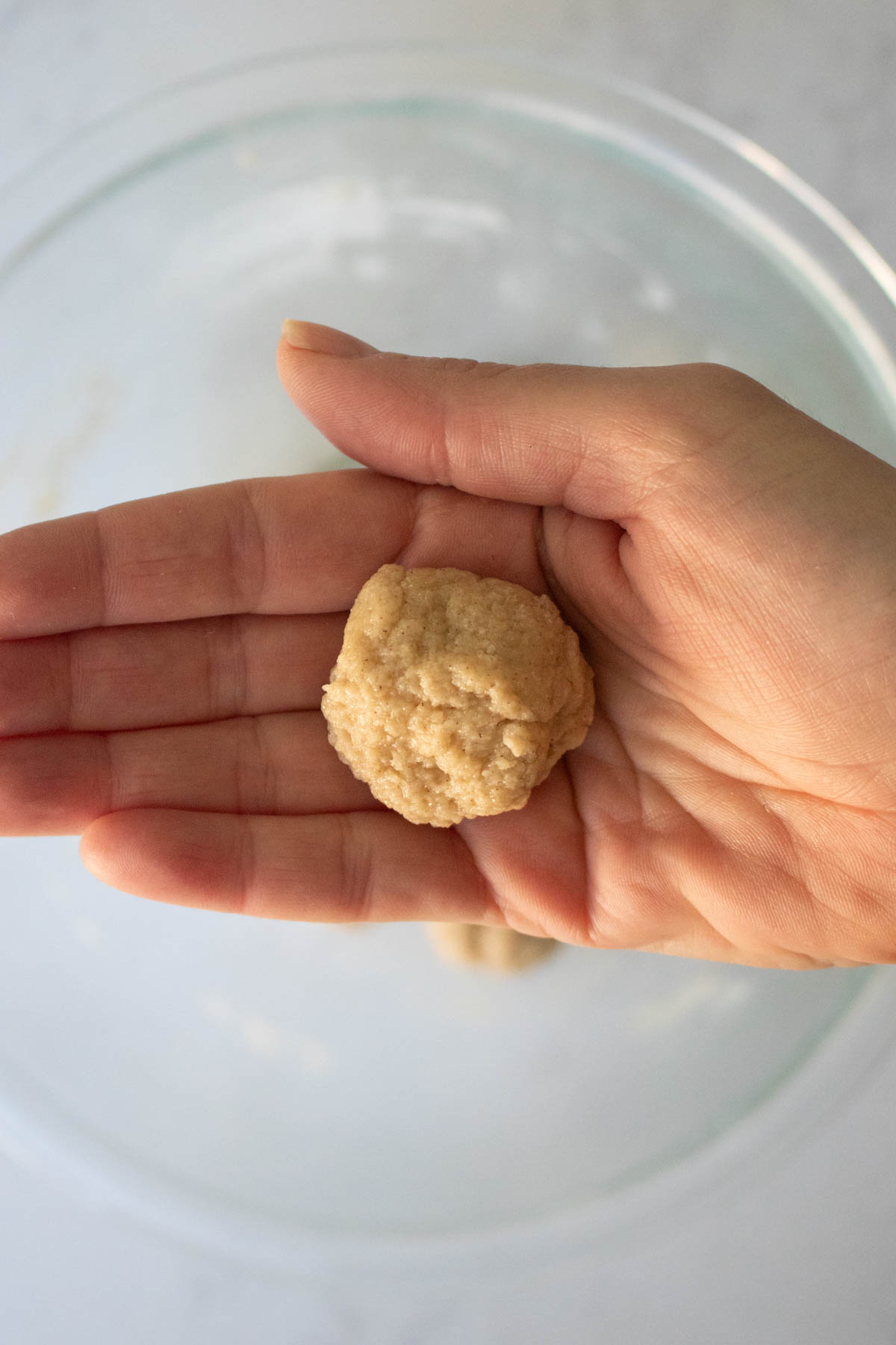 hand holding a rolled dough ball