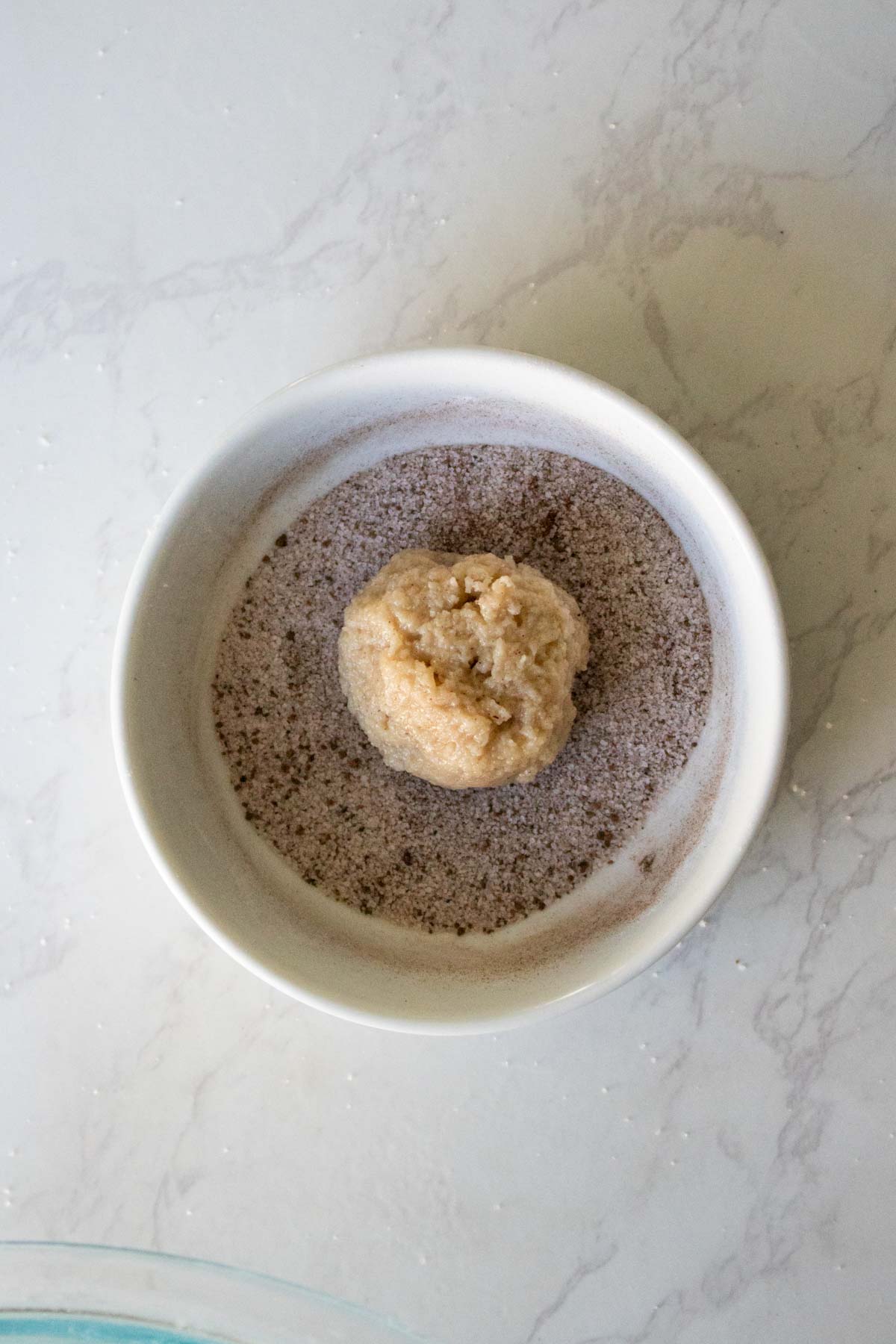 dredging a dough ball in cinnamon sugar