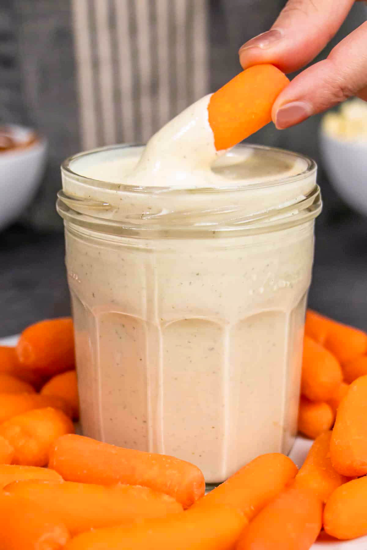 dipping a baby carrot into a jar of cashew ranch