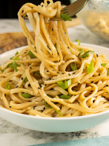 sesame udon noodles in a bowl with green onion