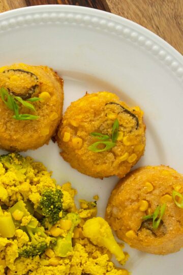 baked grit cakes on a white plate next to a vegetable and tofu scramble