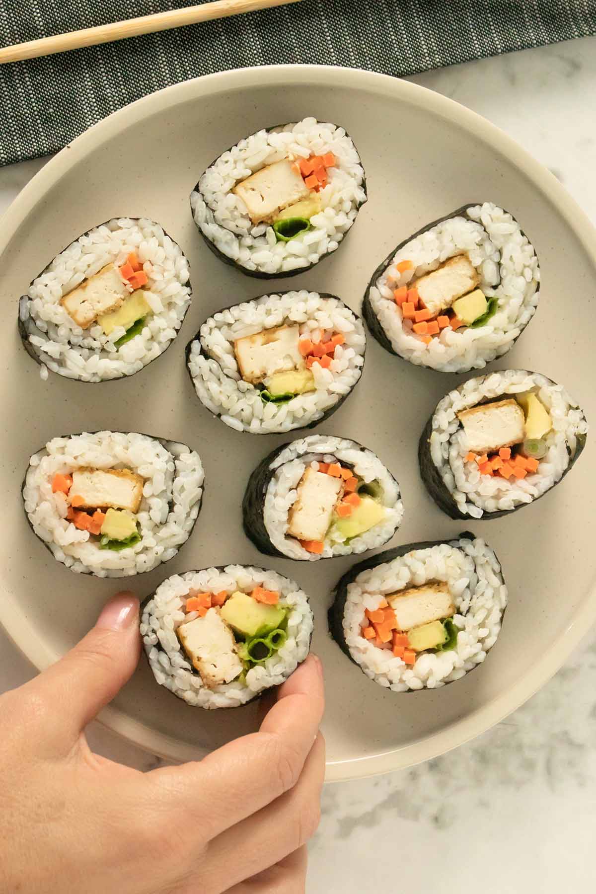 plate of tofu sushi rolls with avocado and pickled carrots