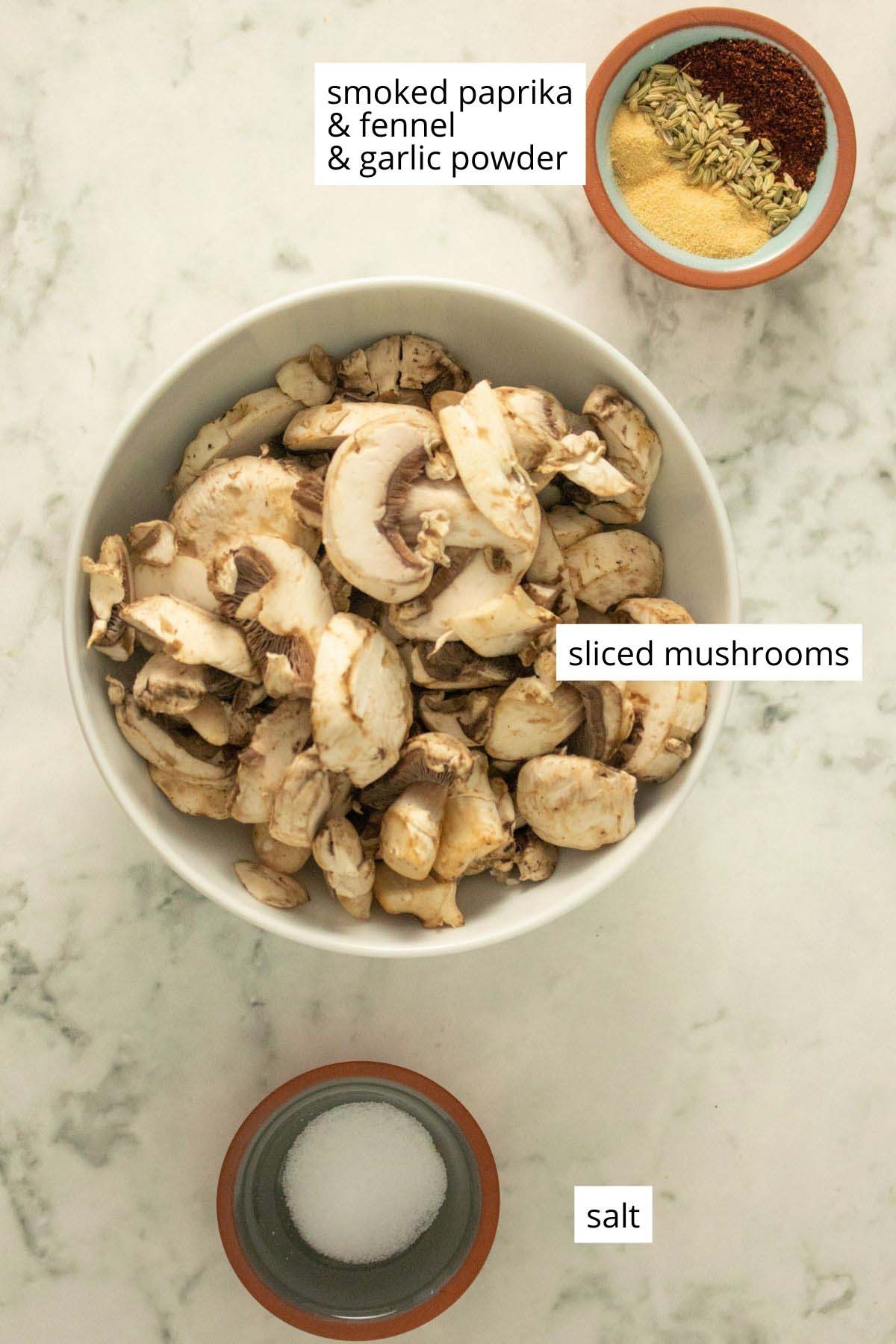 mushrooms, spices, and salt in bowls on a marble table