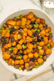 serving bowl of butternut squash and mushrooms with green onion and cranberry