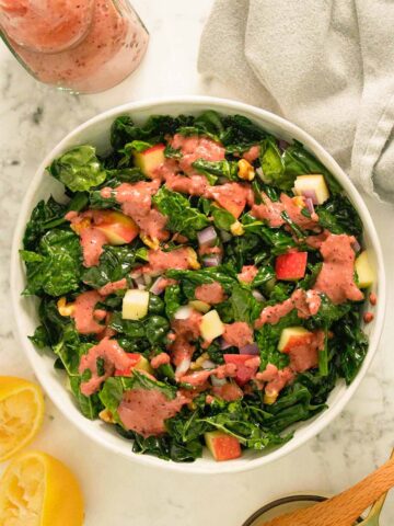 kale apple walnut salad in bowl on a marble table