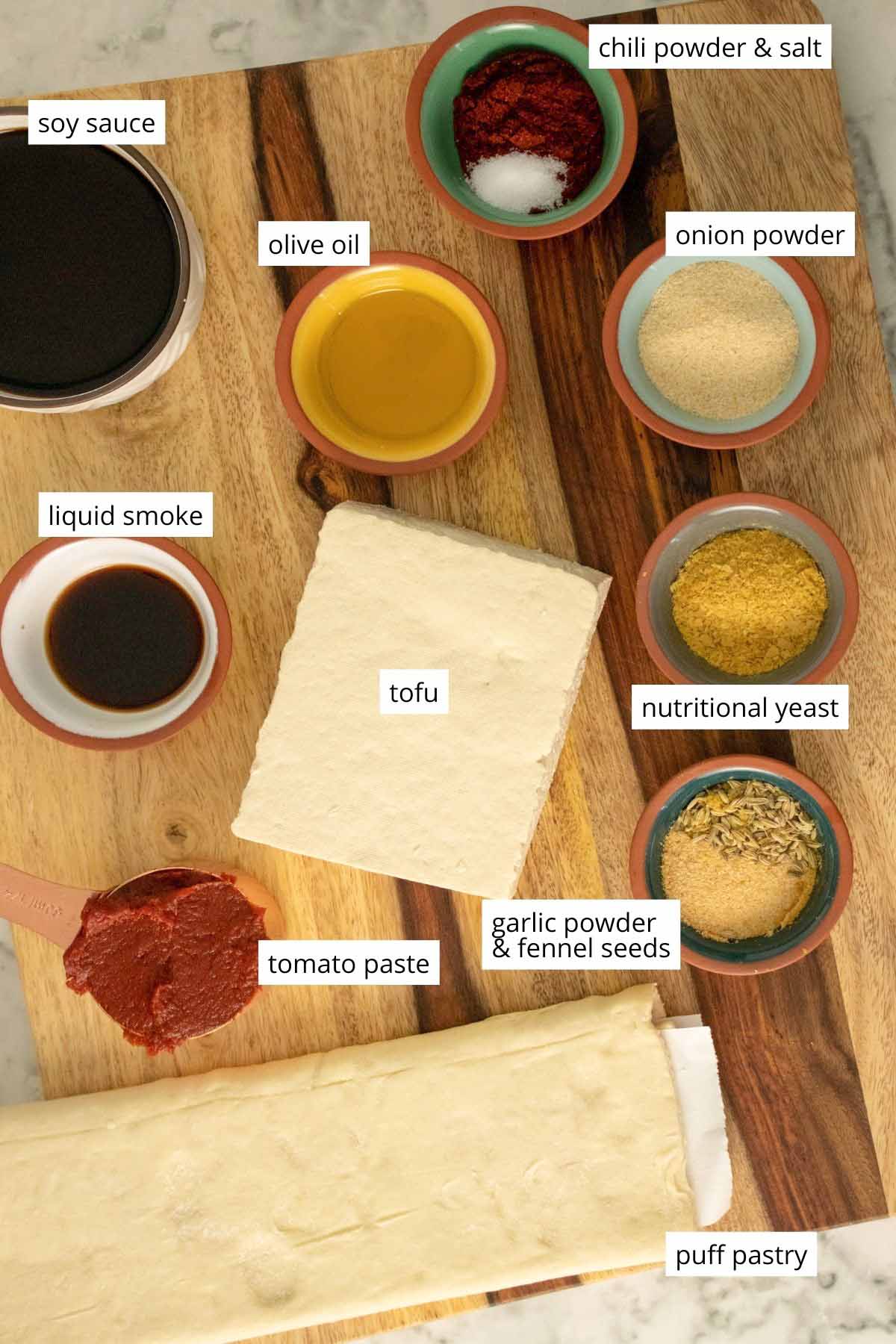 tofu, puff pastry, and lots of seasonings in bowls on a wooden cutting board