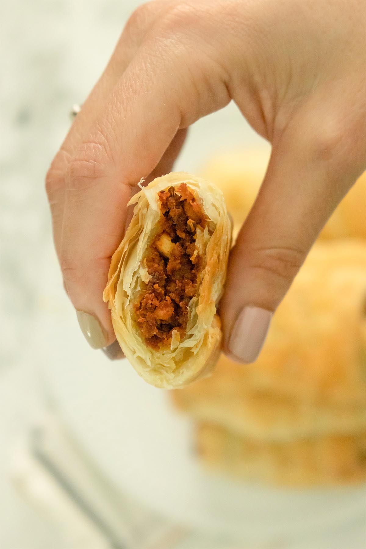 close-up of a hand holding a vegan sausage roll with a bite taken out of it