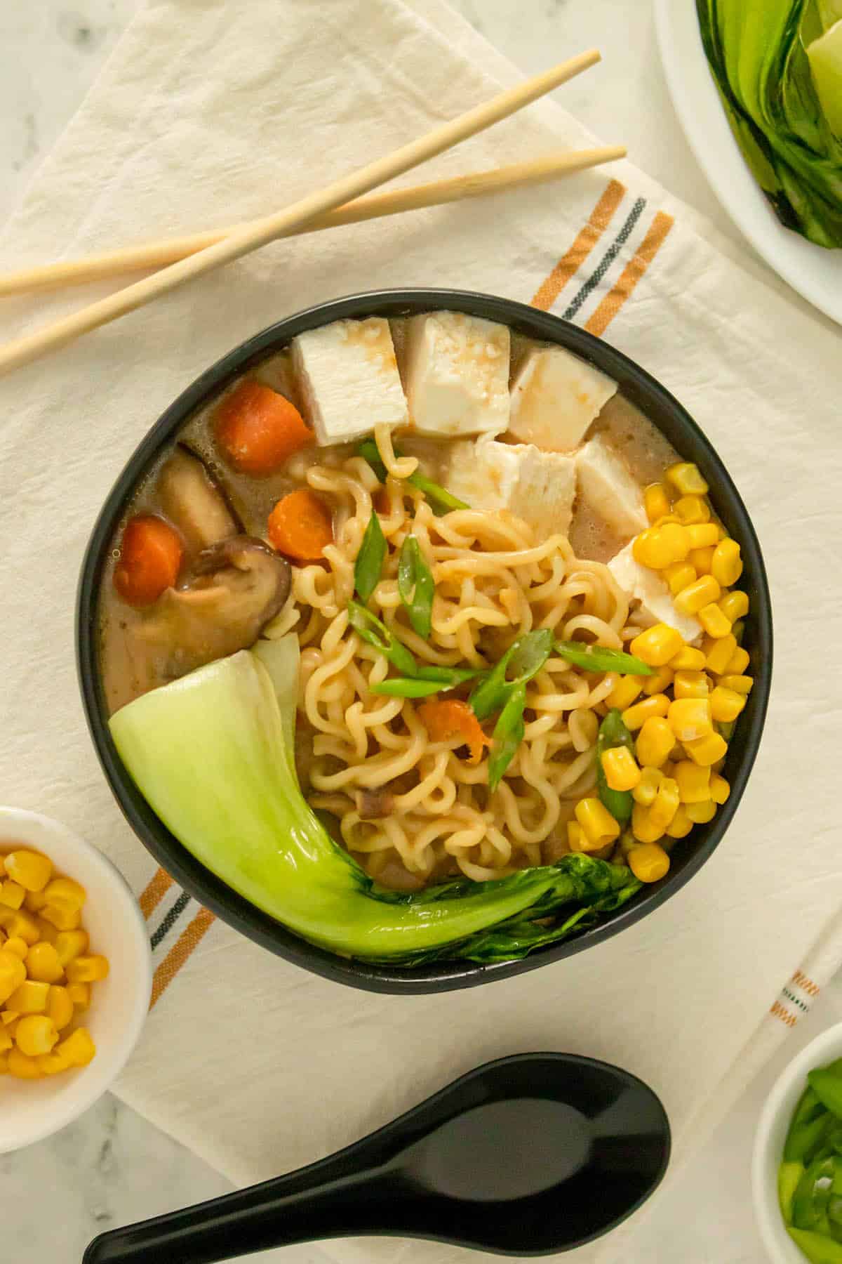 creamy vegan miso ramen in a bowl with bok choy, corn, tofu, carrots, and mushrooms