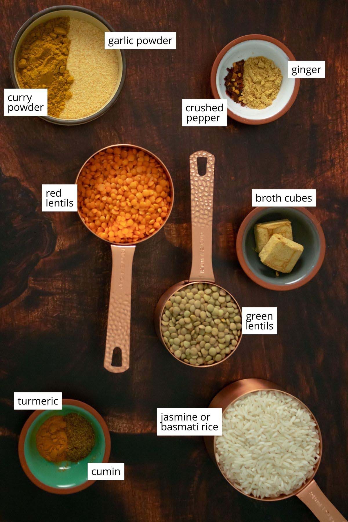 red and green lentils, rice, and spices in bowls on a wooden table
