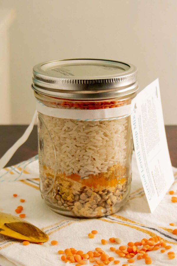 lentil soup mix in a jar with red lentils scattered on the tabletop