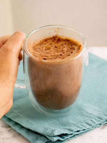 hand holding a mug of maca latte