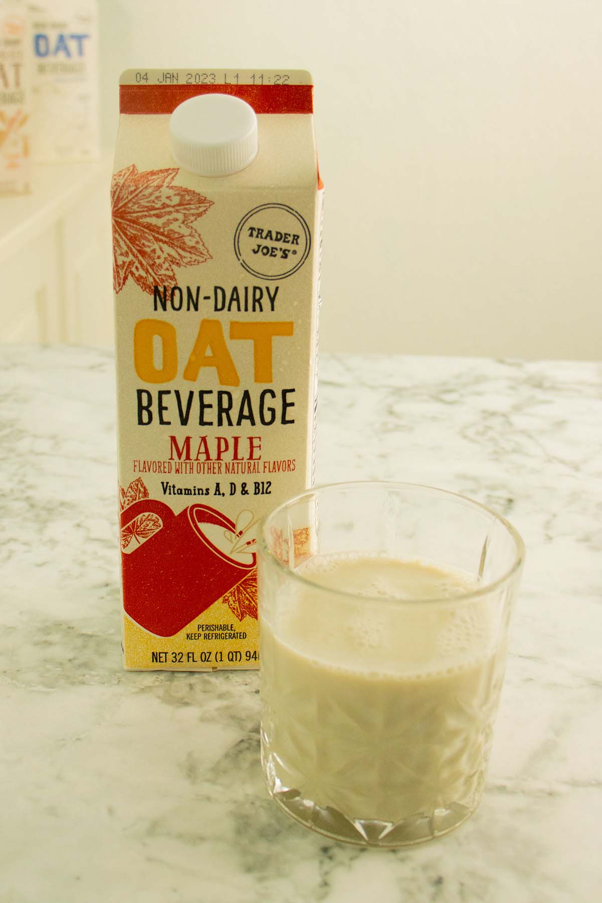 glass of Trader Joe's maple oat milk next to the carton