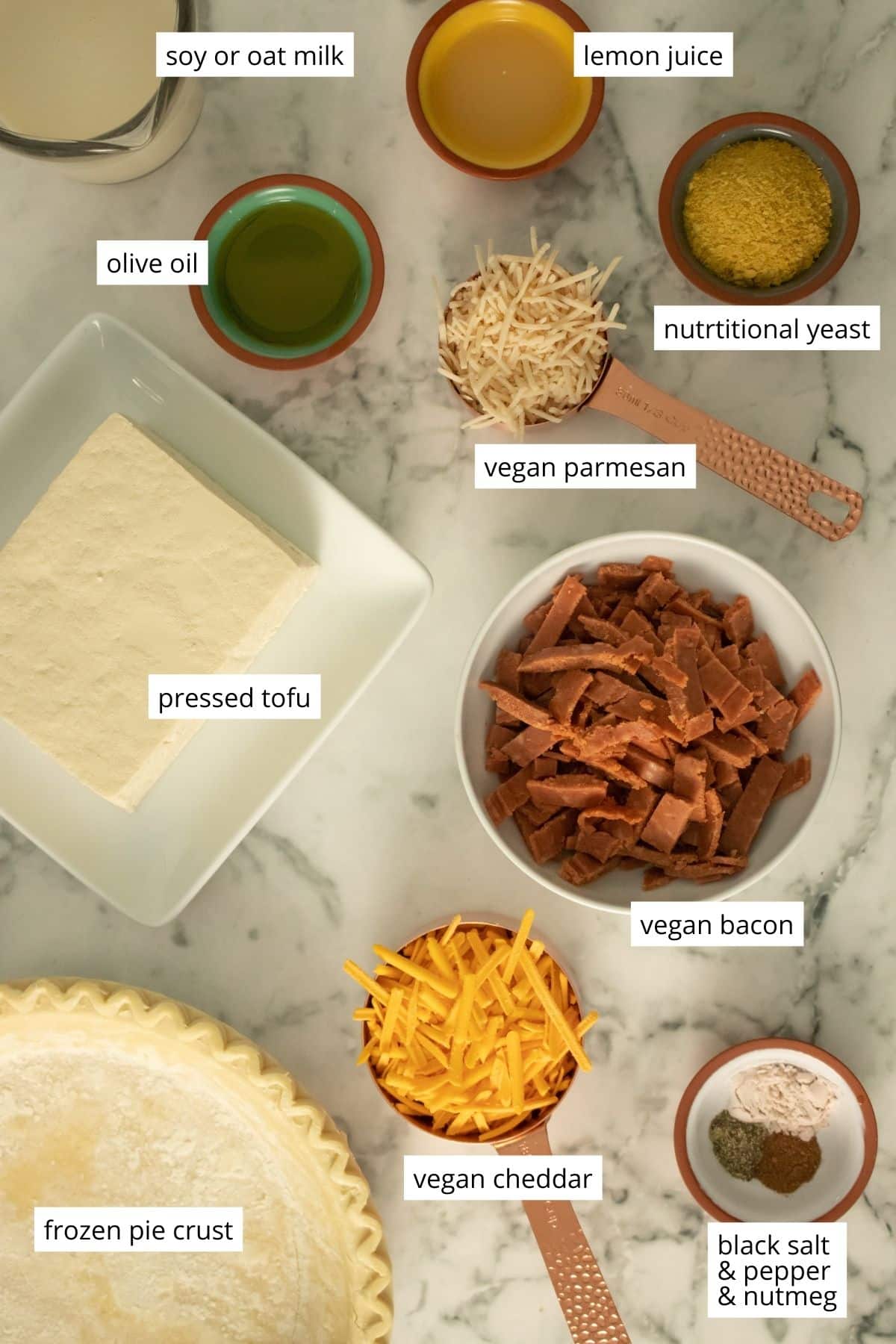 tofu, vegan bacon, and other quiche ingredients arranged on a marble table