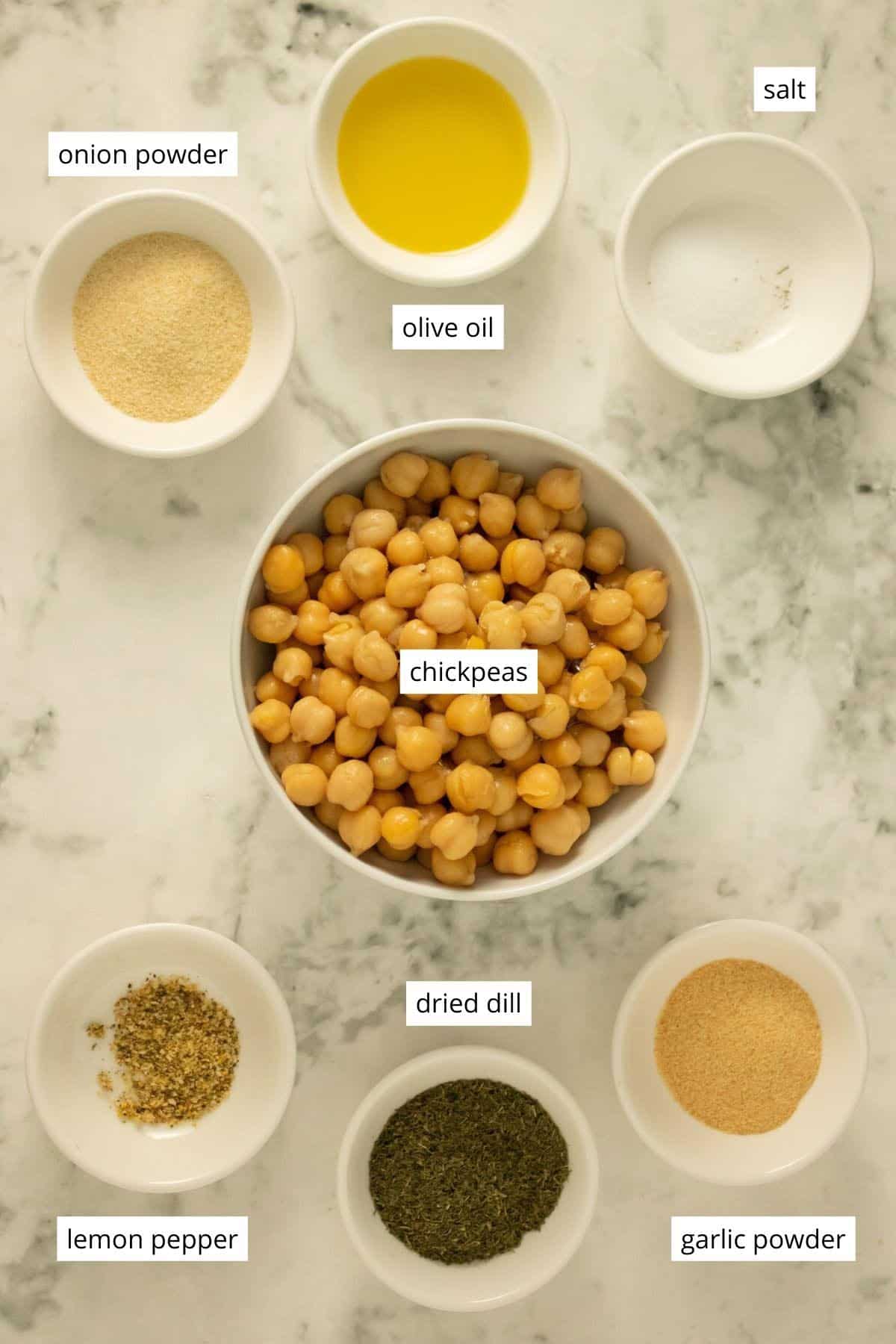 bowl of chickpeas surrounded by ramekins with oil and spices in them