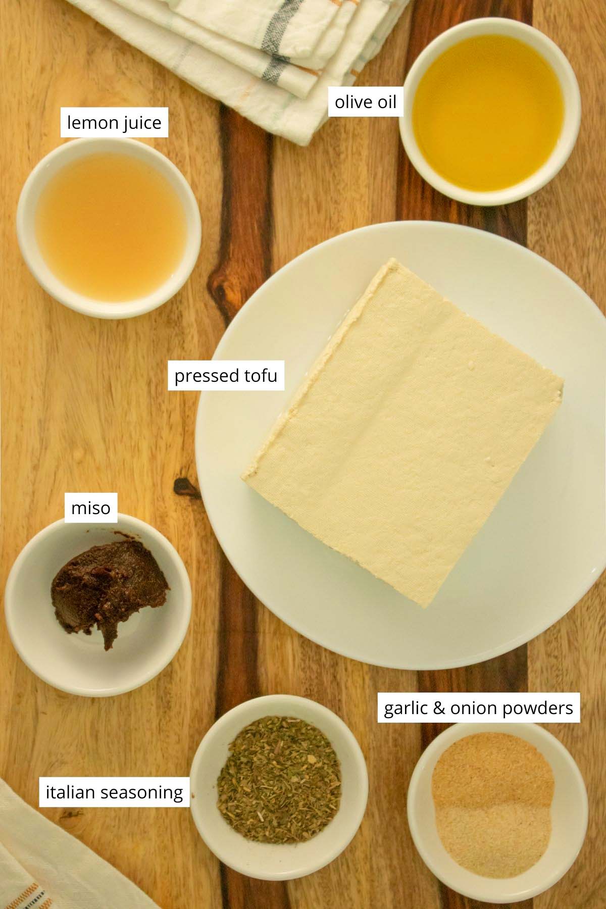tofu and seasonings in white dishware on a wooden tabletop