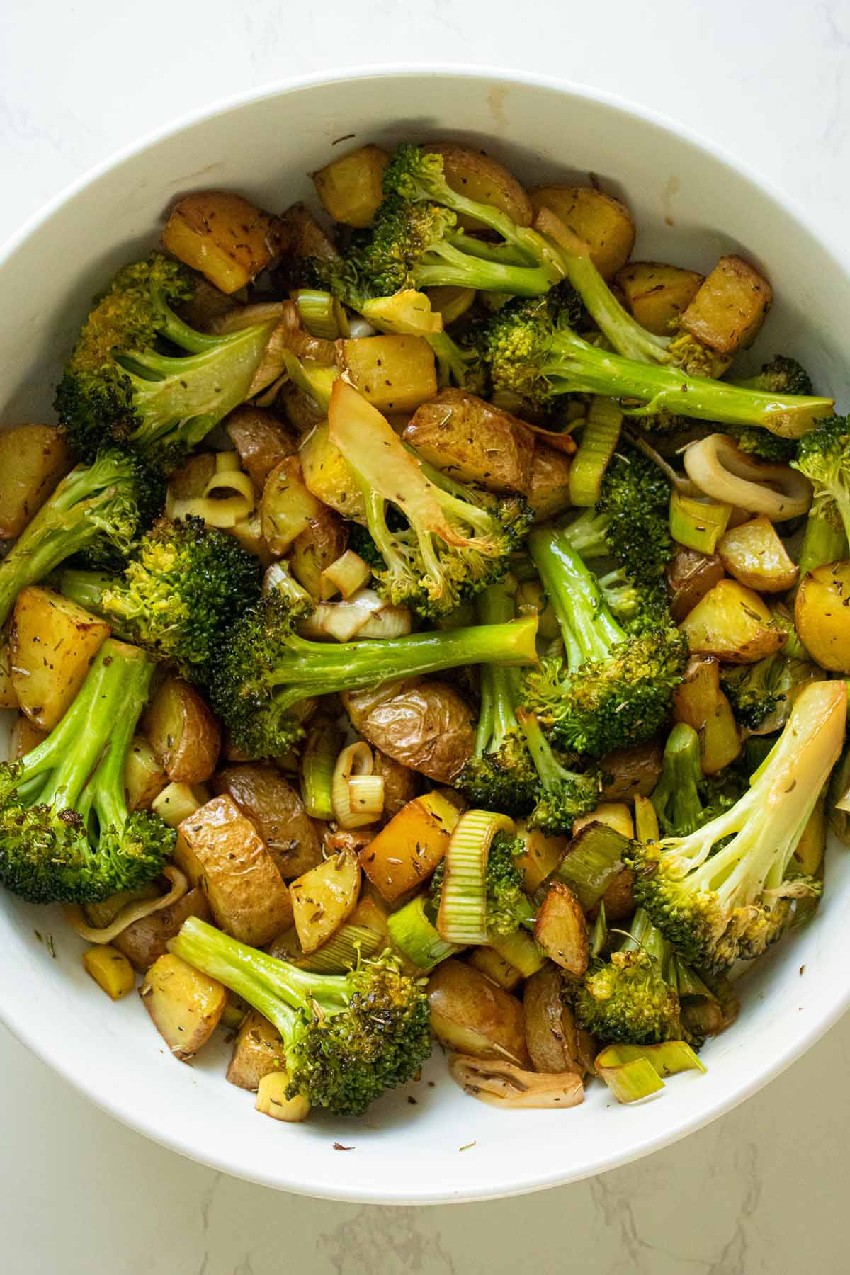roasted potatoes and broccoli in a bowl before adding the sauce