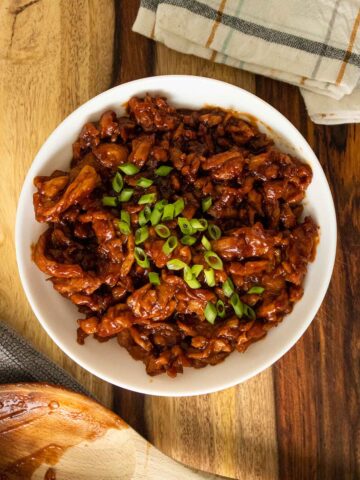 BBQ soy curls in a bowl with green onions on top