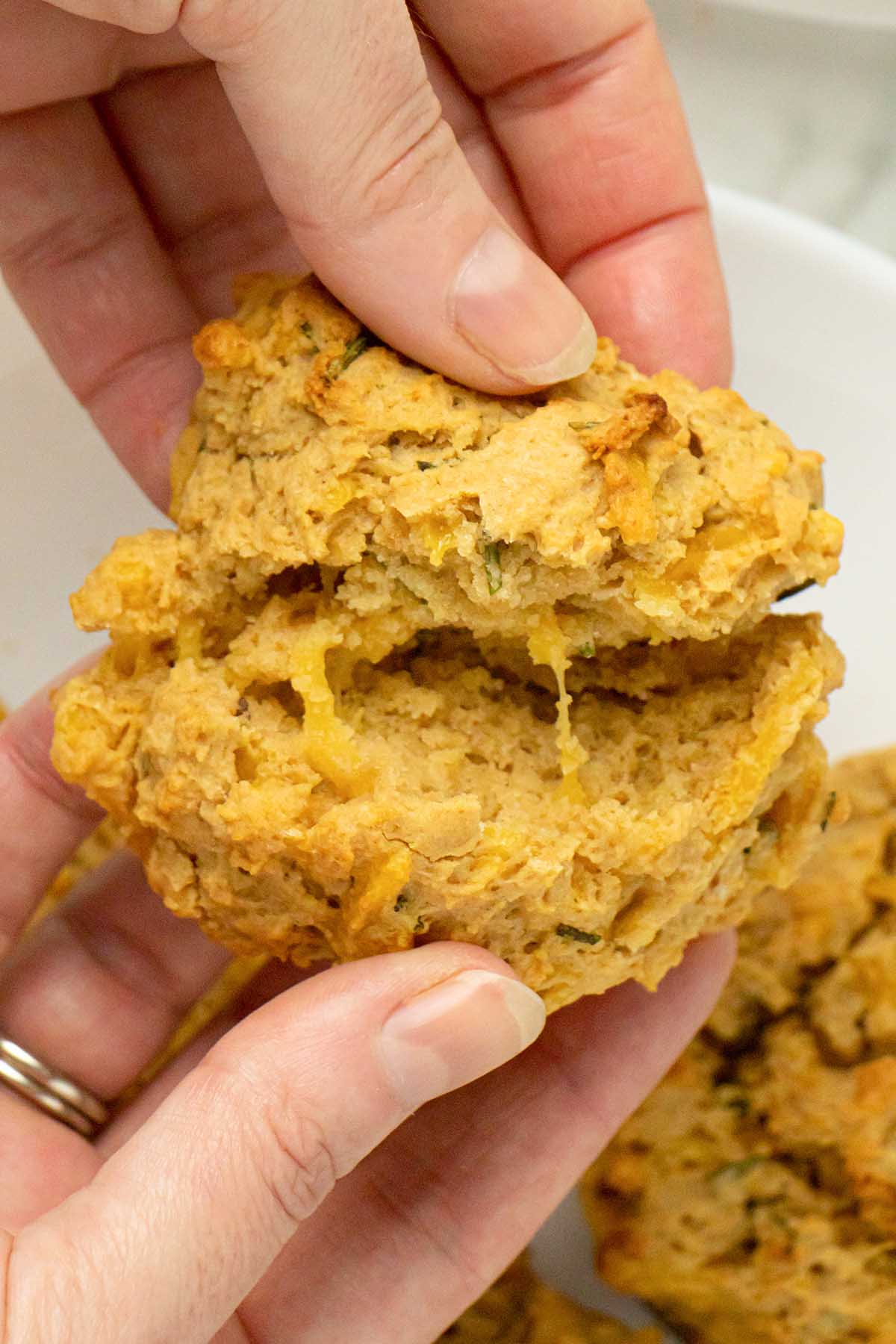close-up of a hand splitting a vegan drop biscuit in half, so you can see the inside