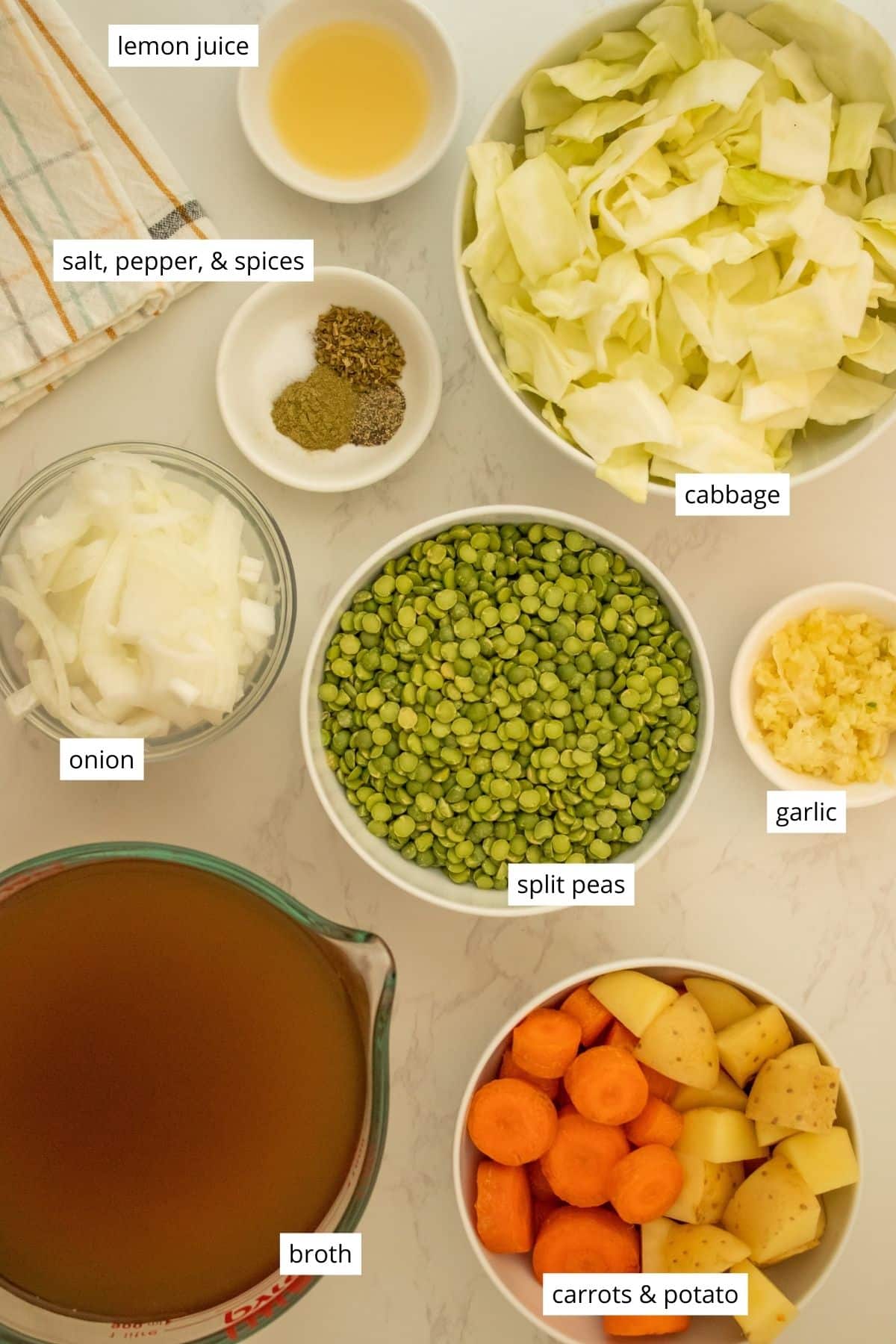 split peas, broth, veggies, and seasonings in bowls on a white table