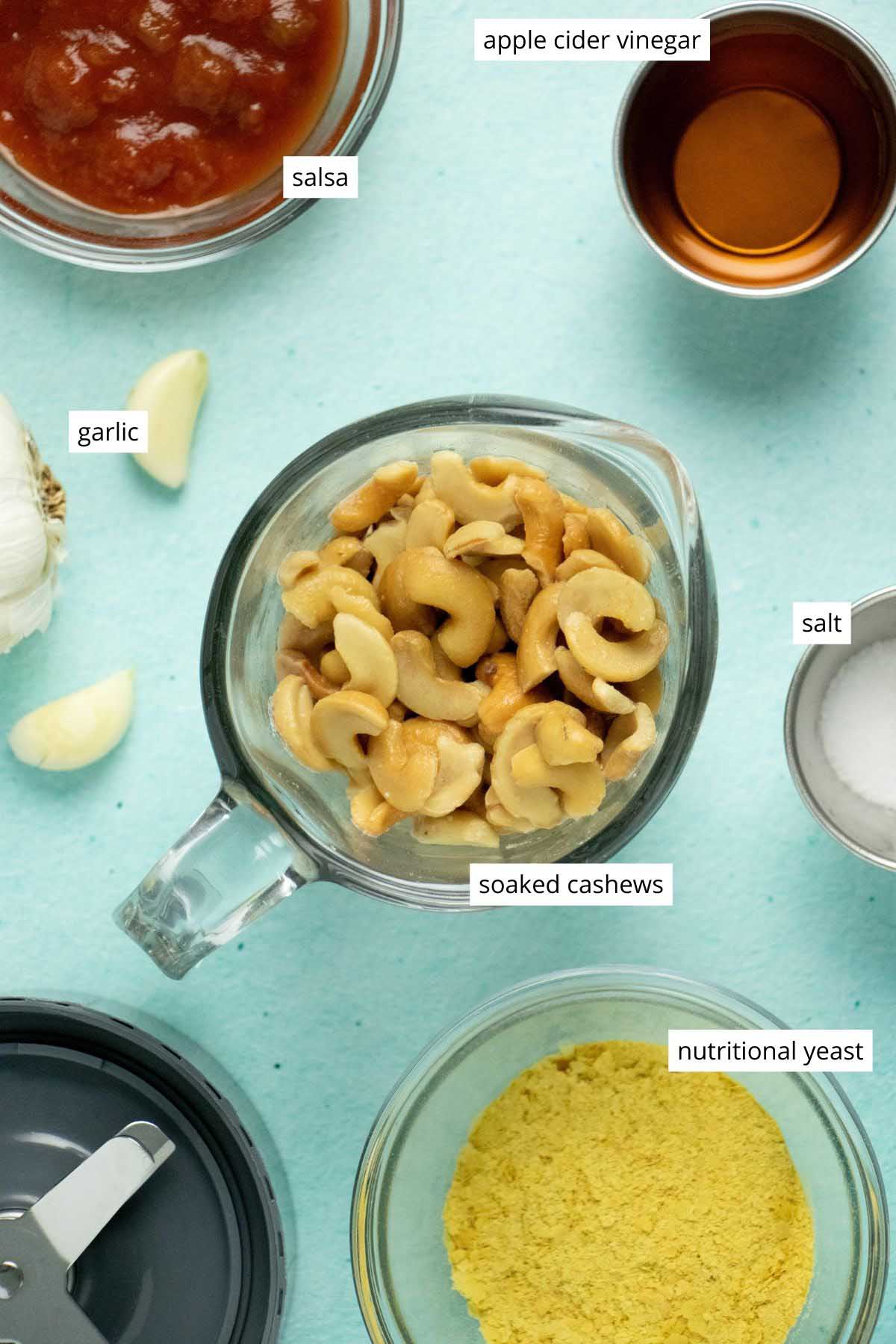 cashews and other queso ingredients in bowls on a blue table