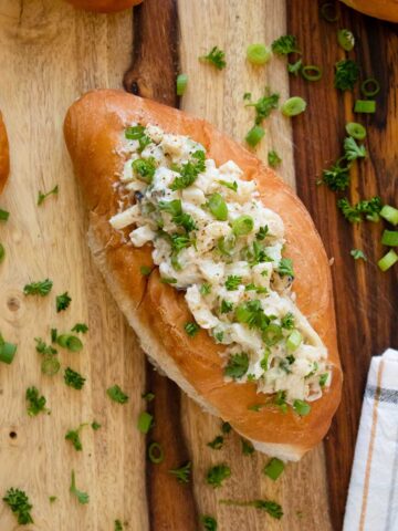 vegan lobster rolls on a wooden tabletop sprinkled with green onion and parsley