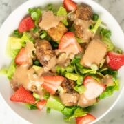 crispy tofu salad in with strawberries and avocado in a white bowl