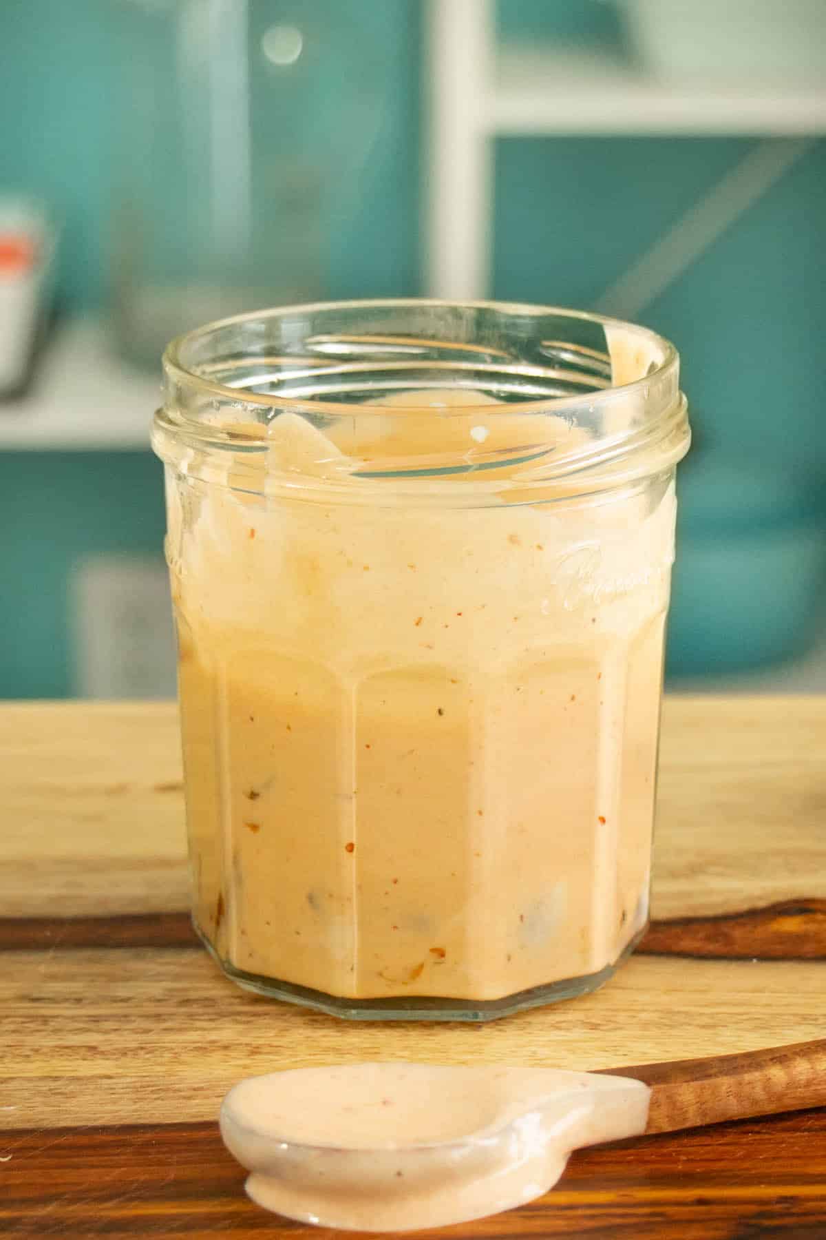 glass jar of vegan chipotle mayo on a wooden cutting board