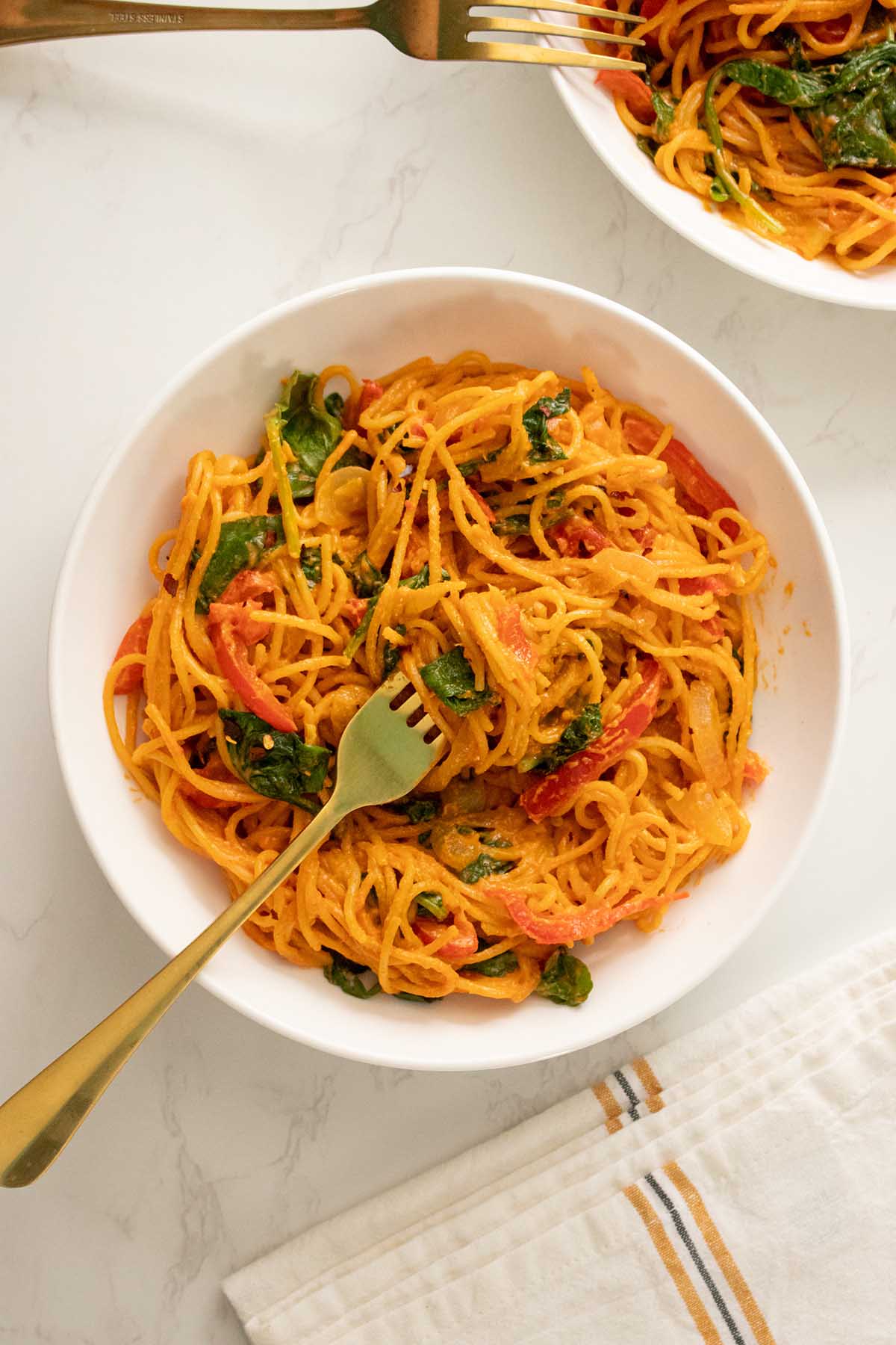 two bowls of gochujang spaghetti with gold forks
