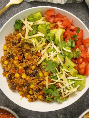 instant pot quinoa burrito bowl with corn, beans, avocado, tomato, vegan cheese, and cilantro