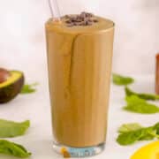 chocolate shake green smoothie on a white table surrounded by some of the ingredients