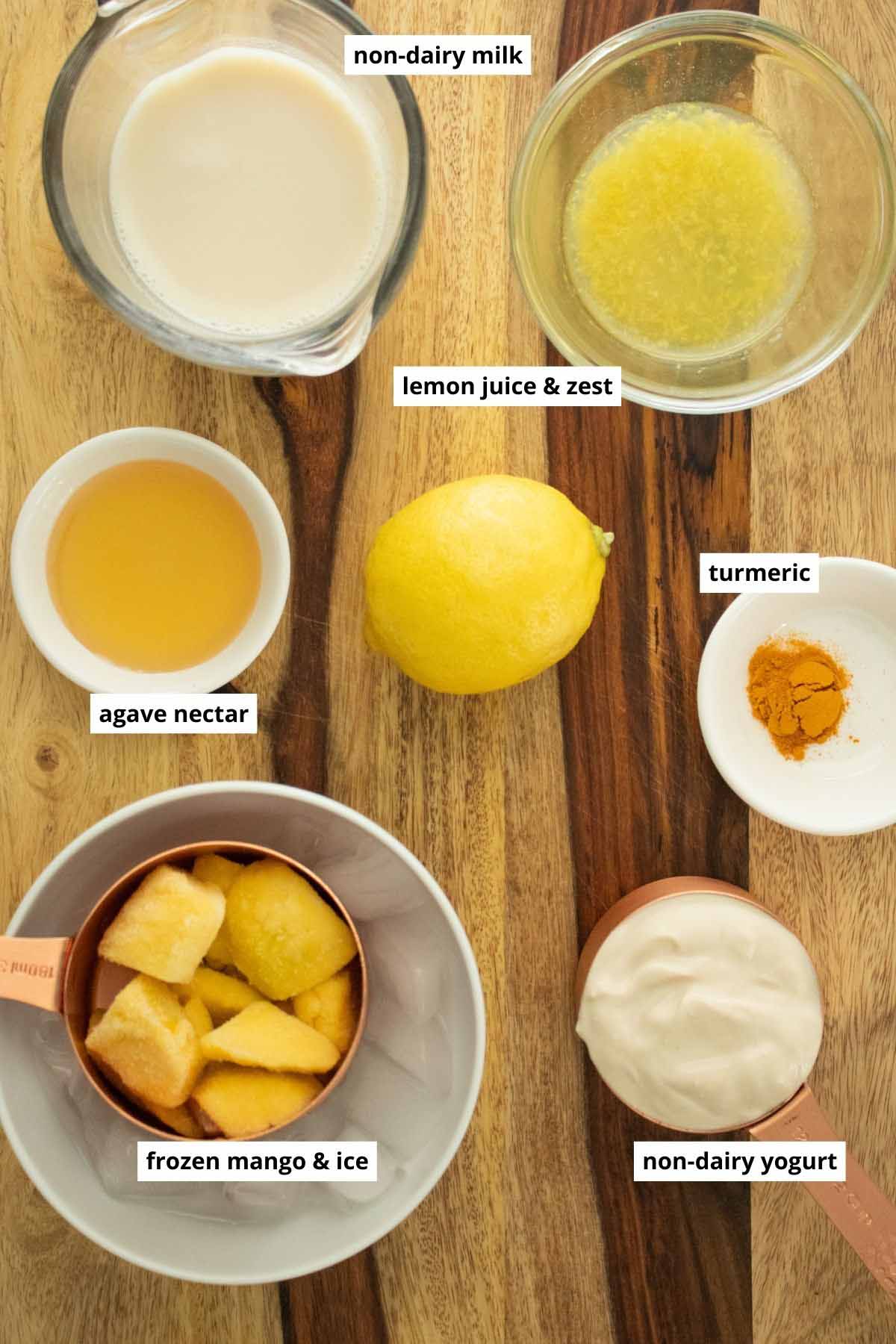 lemon juice and zest, yogurt, and other smoothie ingredients in cups on a wooden table