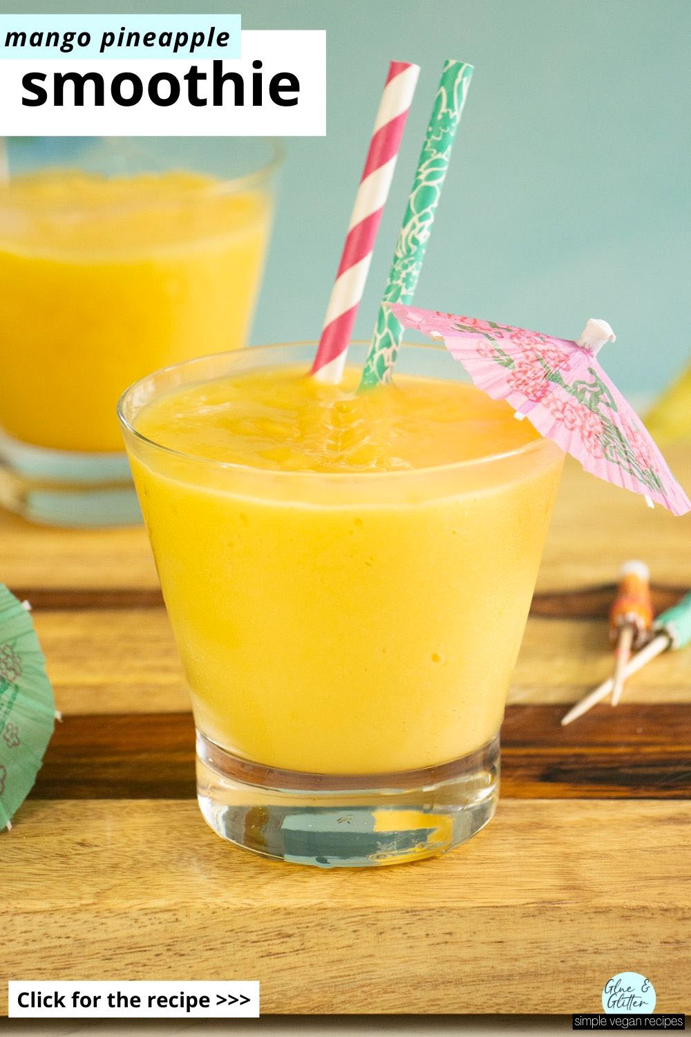 mango pineapple smoothies with umbrellas and straws in them on a wooden countertop, text overlay
