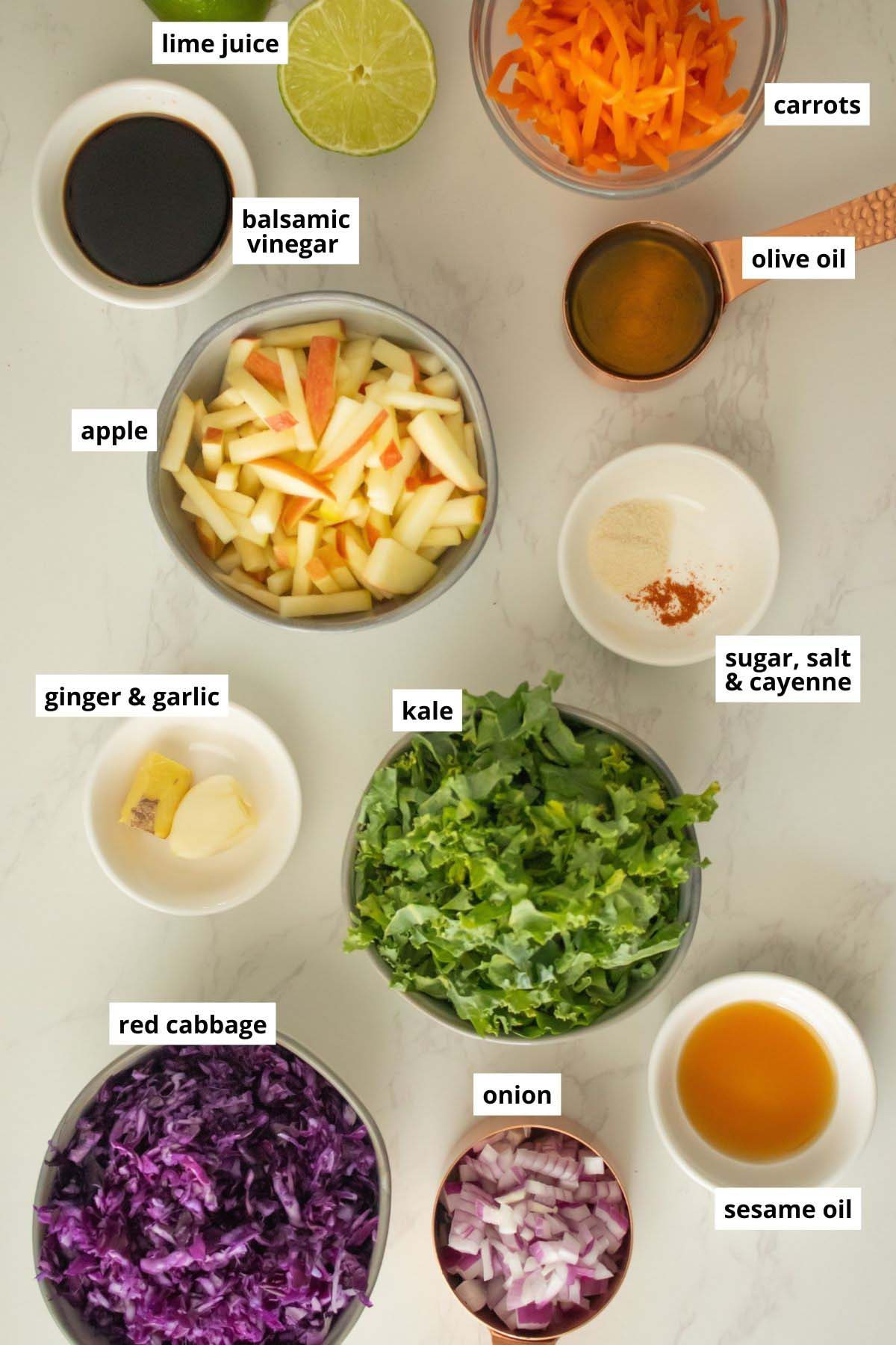 apples, kale, cabbage, and other slaw ingredients in bowls on a white table