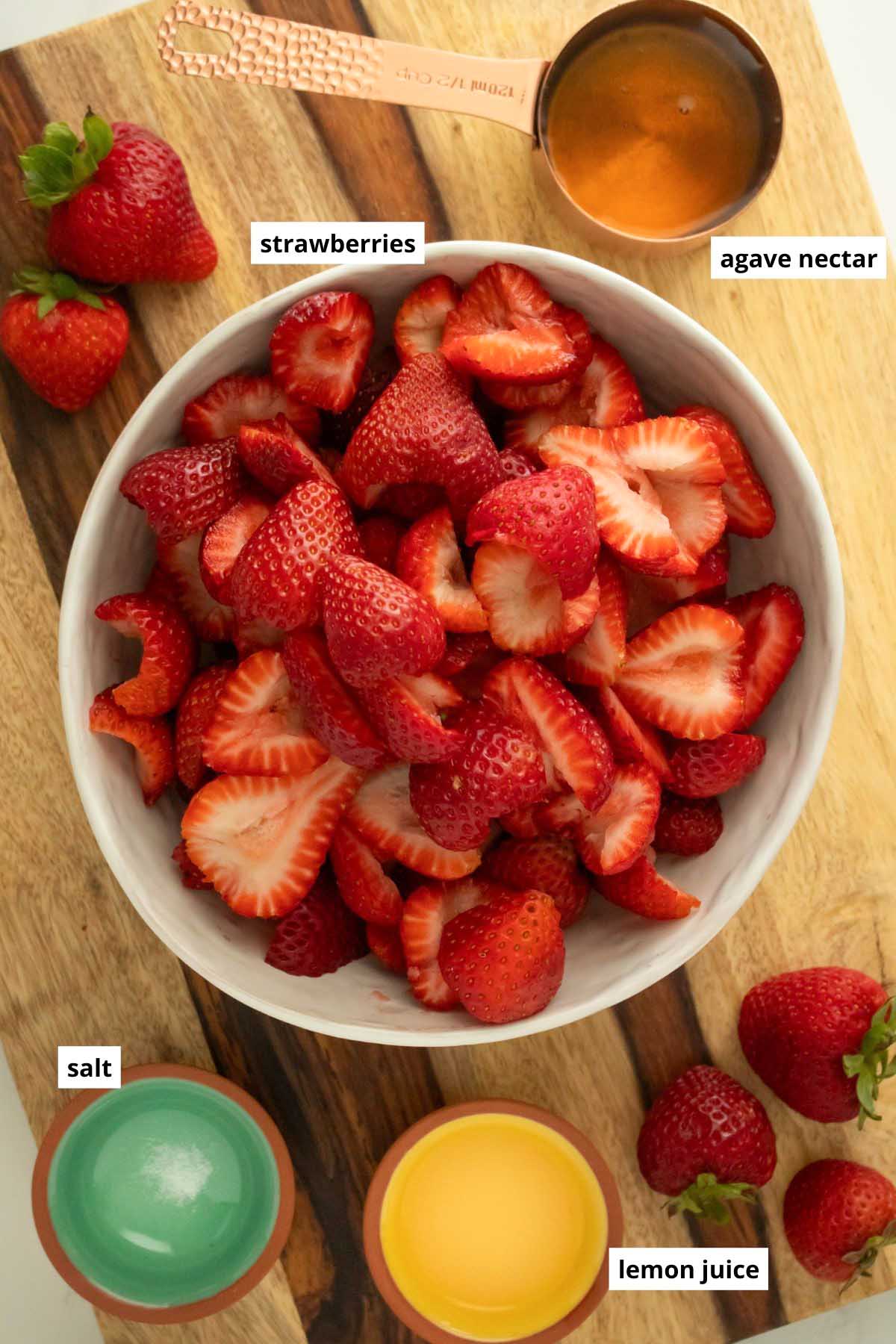 strawberries, agave nectar, salt, and lemon juice in bowls on a wooden table