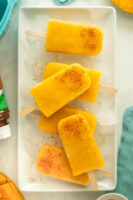 mango tajin popsicles on a serving tray covered in ice