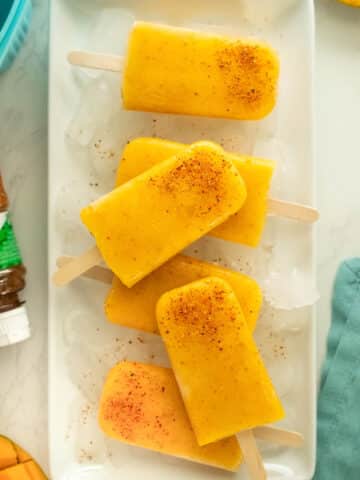 mango tajin popsicles on a serving tray covered in ice
