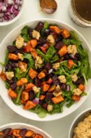 roasted beet and sweet potato salad with arugula and smashed chickpeas in a white bowl