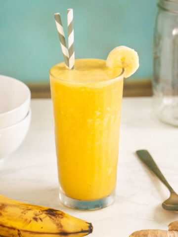 banana turmeric smoothie in a glass garnished with a banana slice