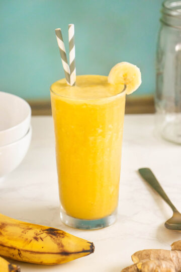 banana turmeric smoothie in a glass garnished with a banana slice