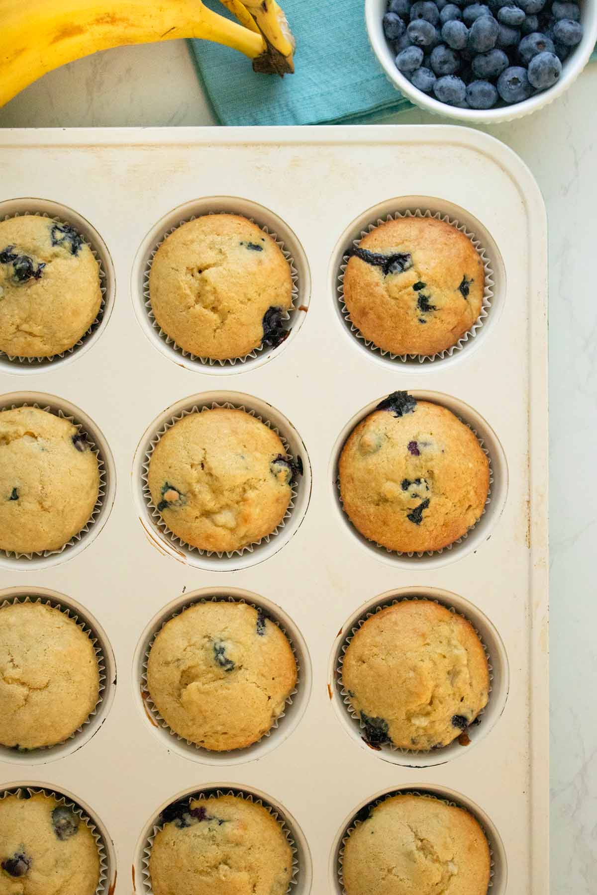 baking pan of einkorn blueberry banana muffins on a white table