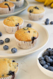 einkorn blueberry muffins plates with blueberries and bananas on the table around them