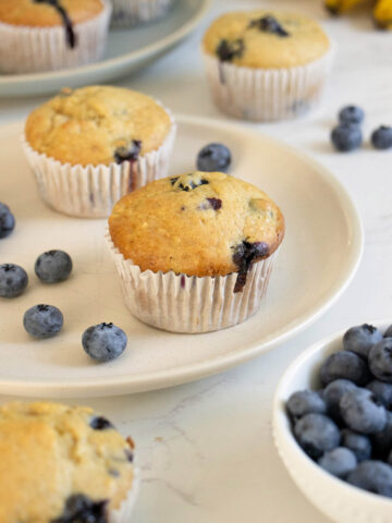 einkorn blueberry muffins plates with blueberries and bananas on the table around them
