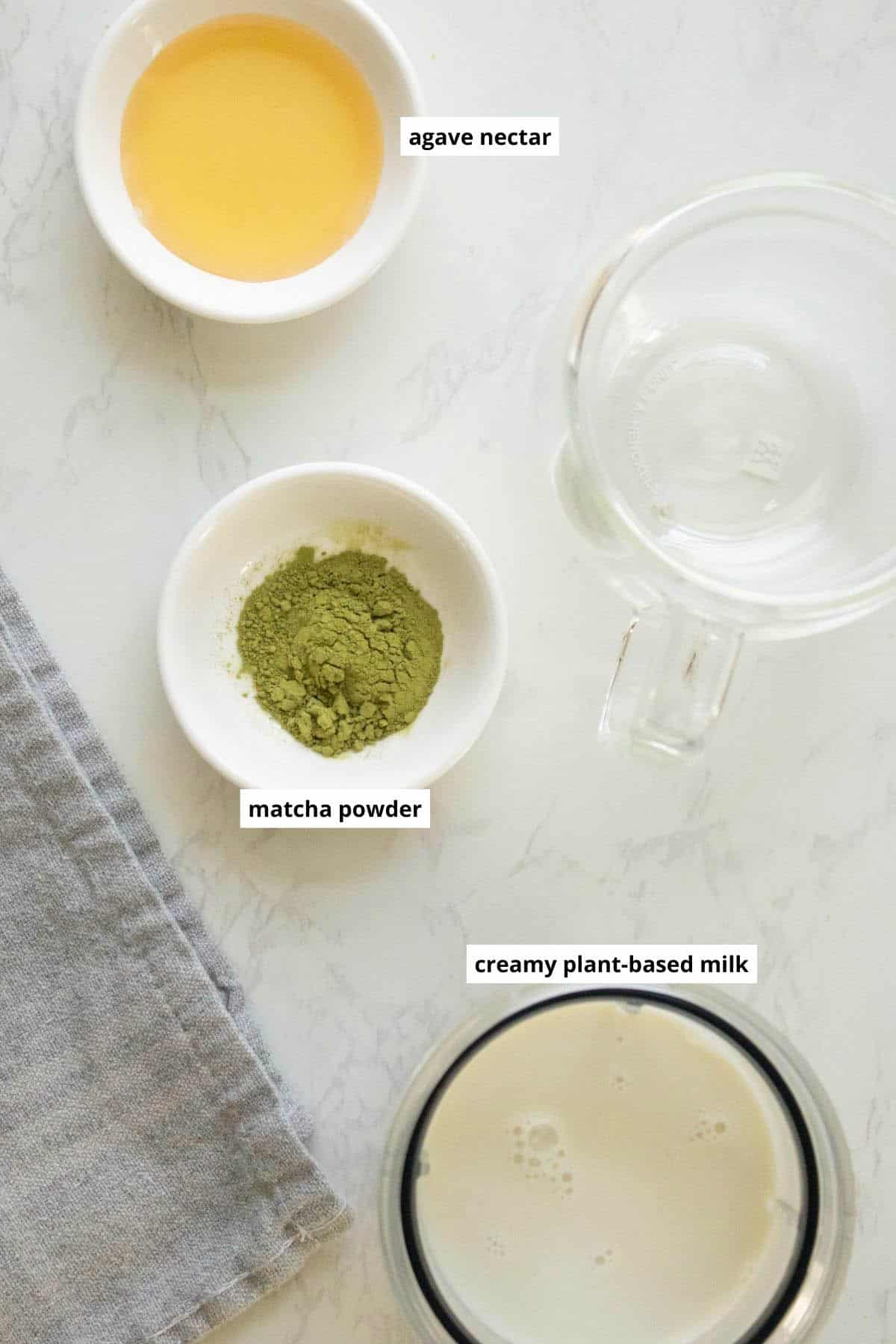 matcha powder, vegan milk, and agave nectar in cups on a white table