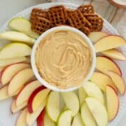 whipped peanut butter yogurt dip with fruit and pretzels for dipping on a white plate