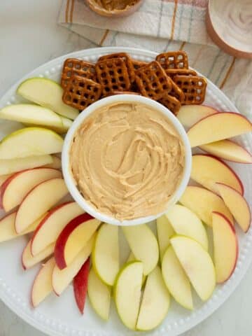 whipped peanut butter yogurt dip with fruit and pretzels for dipping on a white plate