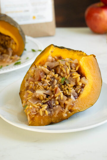 slice of stuffed kabocha squash on a plate with the whole squash in the background